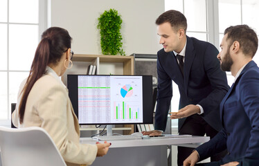 Business team meeting on strategy and data. Colleagues review data on a monitor with infographics...