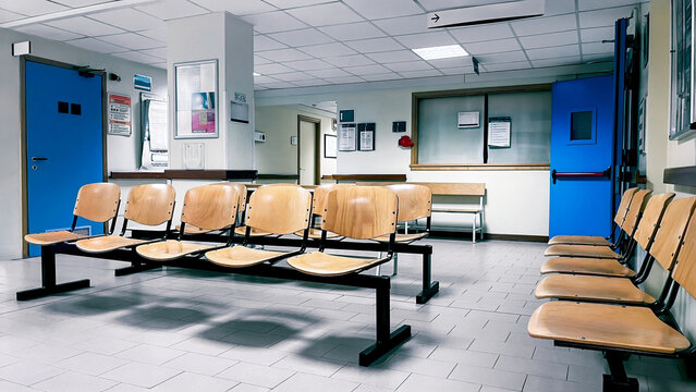 Empty hospital waiting room with rows of wooden chairs and blue doors. Modern clinic hallway and reception area for healthcare, medical services, and public infrastructure concepts