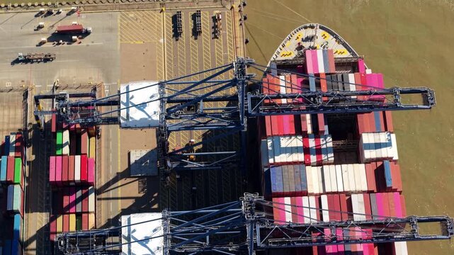 Aerial view of a cargo ship loaded with colorful containers at the bustling Port of Felixstowe, where cranes stand ready for unloading, Felixstowe, United Kingdom.