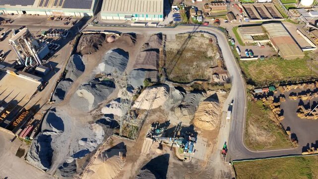 Aerial view of ABP's Port of Ipswich reveals contrasting piles of materials, textures, and tones, under a bright sky, Ipswich, England, United Kingdom.