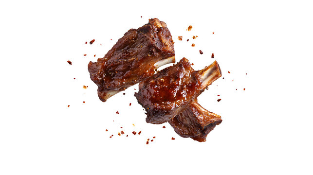 Two barbecue ribs with pepper flakes flying above