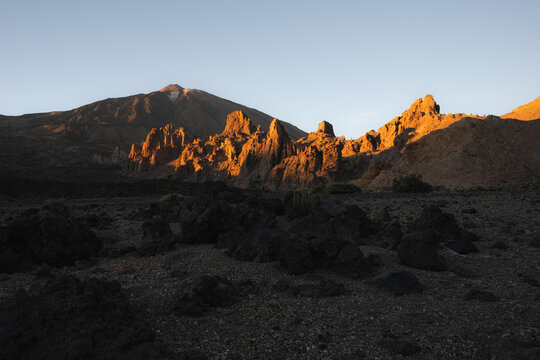 View of the golden light kissing the rugged Roques de Garcia formations and casting long shadows across the volcanic landscape, Teide National Park, Tenerife, Spain.