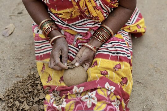 Odisha, India - 26 March 2026: View of a woman's hands adorned with vibrant bangles meticulously crafting a clay pot against the backdrop of her colorful saree.