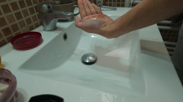Man Squeezes Shaving Gel into Hand for Morning Grooming in a Clean Bathroom Sink