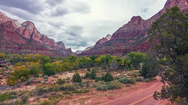 A beautiful, wide-angle view of the iconic Zion Canyon and the Watchman peak in Zion National Park, Utah. The landscape features towering red sandstone cliffs, lush green vegetation in the valley, a w