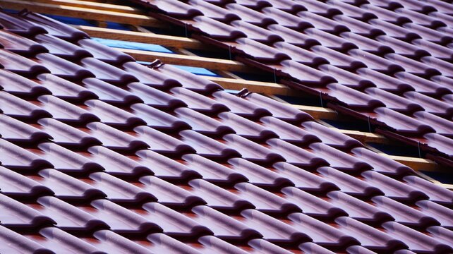 Dach&oacute;wka na dachu, widoczne deski z wierzby, trwają prace dekarskie.