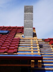 Budowa domu, elegancka dachówka na dachu, deski z wierzby, zamontowany komin, słoneczna pogoda © Adam