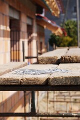 Rusztowanie ustawione przy budowie lub remoncie z widocznymi elementami konstrukcyjnymi i materiałami na platformach. W tle znajduje się dom, podkreślający kontekst prac budowlanych. © Adam