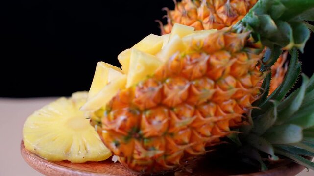 Macro Close-up of Fresh Whole and Sliced Pineapple Rings and Chunks on Wooden Plate, Black Background for Food Ads