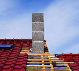 Zamontowany komin, czerwone dachówki i pusta przestrzeń pomiędzy dwoma segmentami. W dachu widać zamontowane okno. © Adam