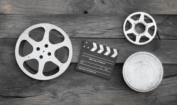 movie clapperboard and film strip on a wooden background