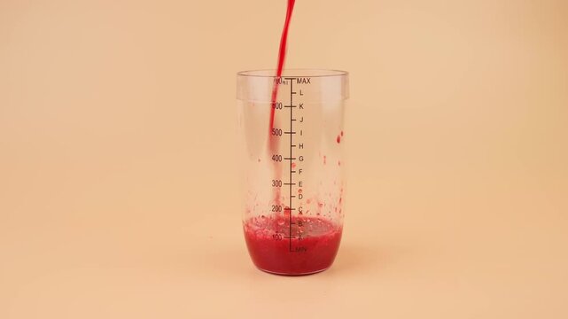 Fresh Red Yangmei Bayberry Fruit Pulp Pouring into Transparent Measuring Cup on Peach Background, Food Commercial, Macro Close-up Texture