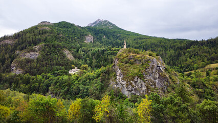 Naklejka premium Clocher Saint Julien de Méolans bell tower rising above a river, French Alps, Alpes-de-Haute-Provence, France, Europe.