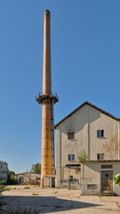Fototapeta premium Old industrial buildings and brick chimney on a sunny day with clear blue sky in Berlin, Germany 