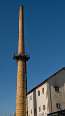 Fototapeta premium sunny old industrial brick chimney on a clear blue sky