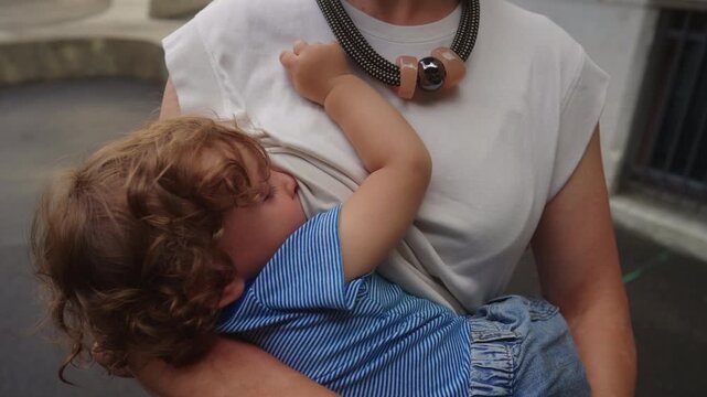 Toddler breastfeeding while resting against mother chest showing attachment bonding comfort and deep emotional connection in nurturing outdoor family moment
