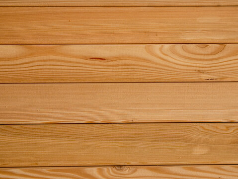 Clean architectural light brown wooden planks featuring natural grain patterns knots horizontal alignment smooth finish providing organic timber background material.