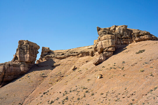 Massive sandstone outcrops and jagged crests perched atop a barren desert ridge in Charyn Canyon, Kazakhstan