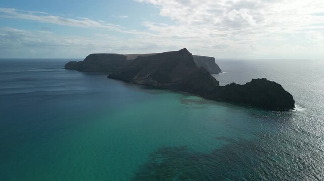 Aerial view of drone flying over Ilheu da Cal, a small rock island in Porto Santo, Madeira, Portugal. Portuguese paradise with clean transparent water.