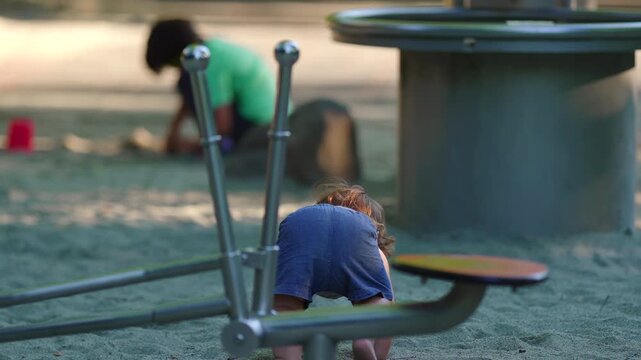 Toddler walking in sandbox briefly losing balance then transitioning into crawling capturing adaptation resilience and continuous outdoor exploration during playful childhood moment