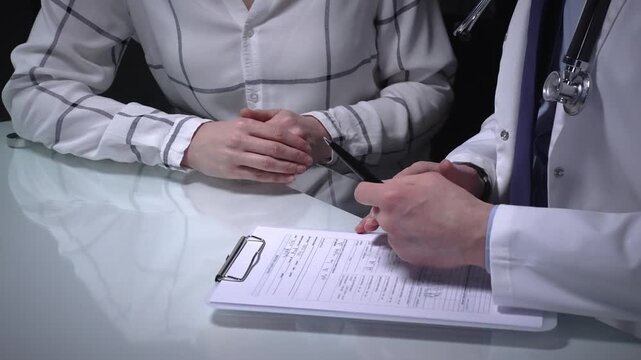 Doctor consulting with patient in medical office, writing notes on a document during a discussion about health, providing professional healthcare and advice, overwork