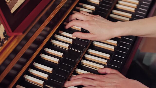 Hands of a professional musician playing a vintage harpsichord with reversed key colors