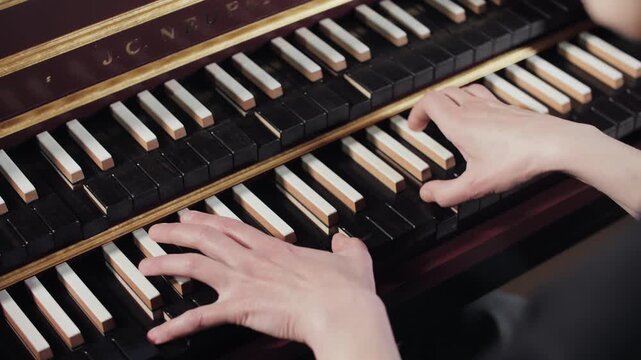 Professional musician playing a vintage double manual harpsichord with inverted keys