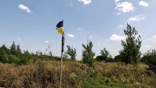 View from move car on torn national flag waves proudly on road sign at frontline city in Ukraine. Scene symbolize resilience and unbroken spirit of ukrainian people, failure of invading russian forces