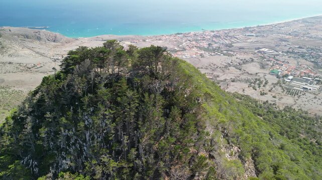 Aerial view of drone flying around Pico do Castelo mountain, with a shape of a vulcano. Porto Santo Island, Madeira, Portugal. Airport and long beach in the background