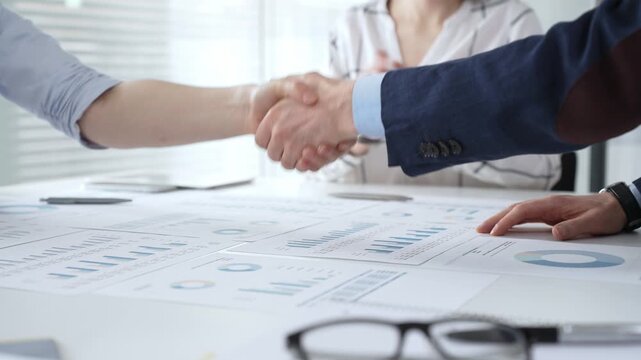Business executives shaking hands, sealing an agreement after successful negotiations in a bright office, symbolizing partnership, collaboration, and a mutually beneficial deal signing