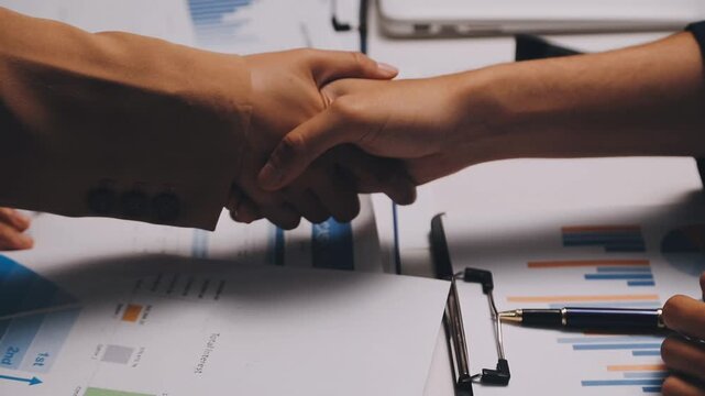Business people shaking hands above contract papers just signed on the wooden table, close up. Lawyers at meeting. Teamwork, partnership, success concept