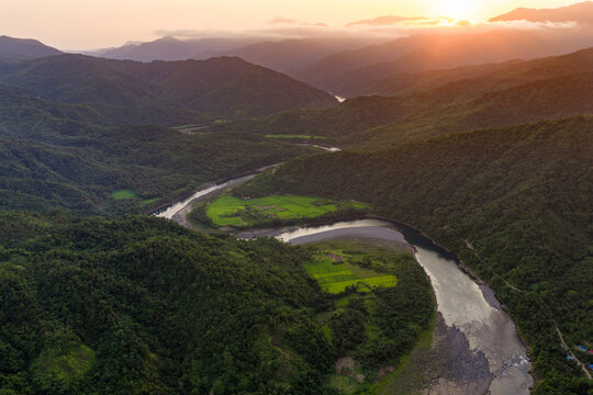 Scenic Panorama Aerial Drone Picture of the meandering blue Agos River, Valley, and Rice fields near Infanta, Quezon Province in Luzon, Philippines during Sunset