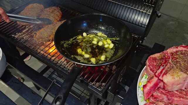 barbecue party outdoors, cooking stacks of grilled meat, rib eye steak, garlic, rosemary, butter in a pan, pieces of raw meat