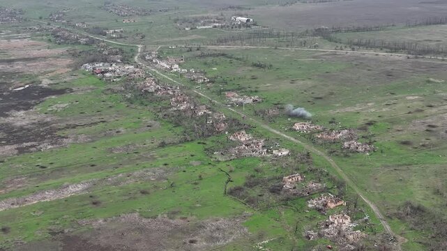 Aerial drone footage of artillery strikes on a tree line in a foggy combat zone.