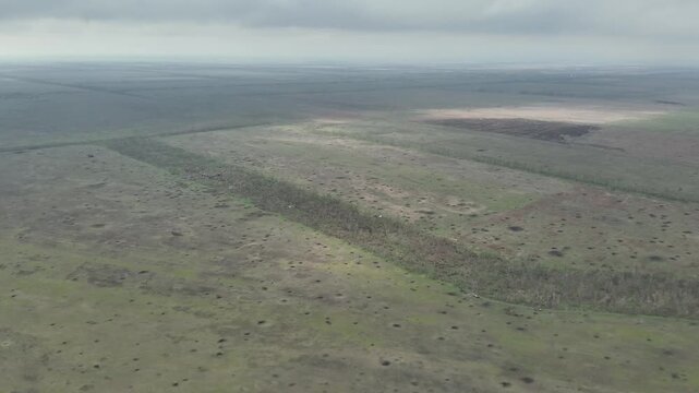 Aerial drone surveillance of fields densely covered with shell craters in a combat zone.