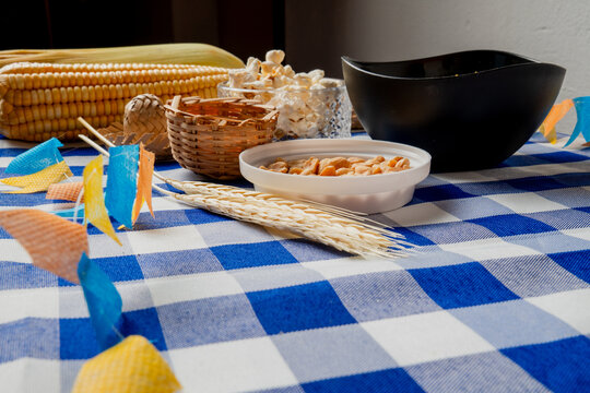 Close-up of Festa Junina snacks with peanuts corn popcorn and flags on blue checkered tablecloth