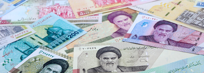 Obraz premium Iranian rial money banknotes pile on table. Iran bills of IRR currency close up. Concept of economy