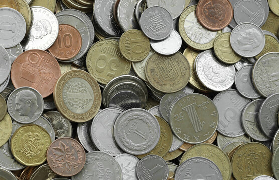 Pile of global currencies, various coin types visible up close. Different nations money together