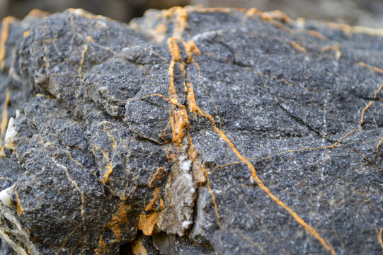 Metamorphic rock with quartz veins and mineral layers on a beach in italy