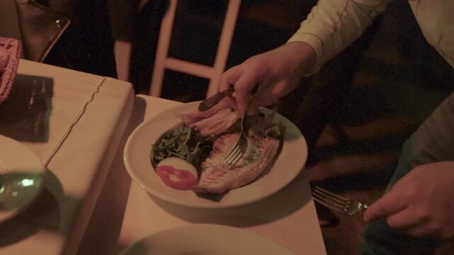Waiter deboning fresh grilled fish for customers