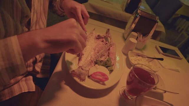 Customer deboning grilled fish at a seafood restaurant