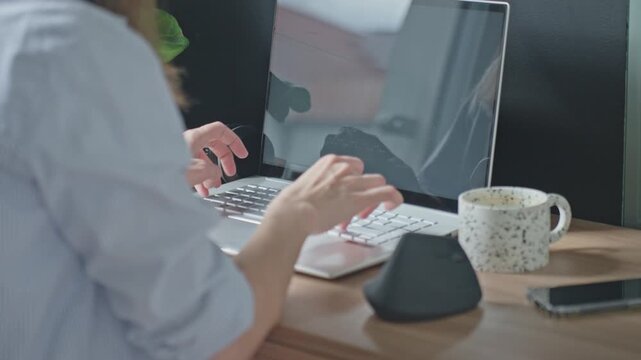 Woman typing on keyboard at desk with mug and smartphone. Concept of remote work, home office and digital communication
