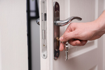 Naklejka premium Man opening door with keys at home, closeup