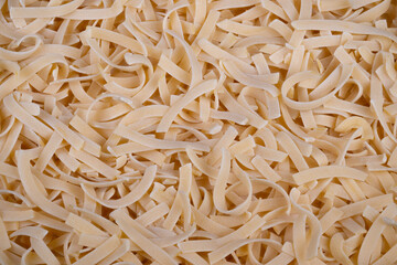 Fototapeta premium Detailed view of homemade egg noodles featuring rough textures and dusting. Closeup shot emphasizing handcrafted nature and textured surface of fresh egg noodles