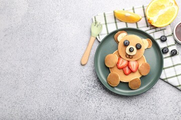 Obraz premium Creative serving for kids. Cute bear made of pancakes, fruits and jam on grey table, flat lay. Space for text