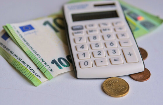 Calculator with Euro Banknotes and Coins on Grey Surface &mdash; Personal Finance Budget Money Calculation Concept