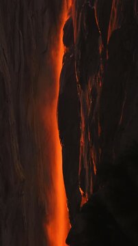 Vertical Screen: Yosemite National Park Firefall phenomenon creates stunning orange glow as sunset light illuminates Horsetail Fall cascading down dark granite cliff face