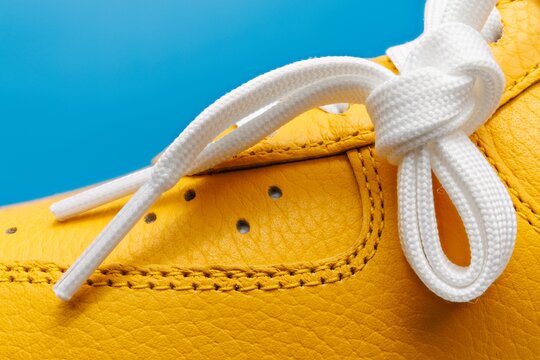 Vue macro extreme d'une basket jaune sur fond bleu uni
