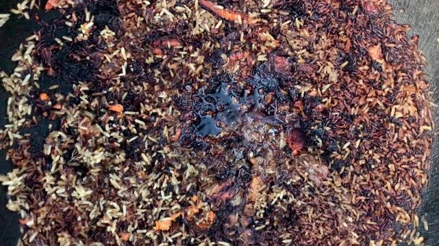 Charred pilaf rice in cauldron, home cook attempting salvage with wooden spoon, burnt crust and blackened grains, scattered carrot.