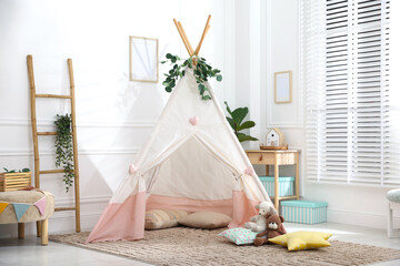 Toy wigwam with pillows, furniture and floral decor in room © New Africa